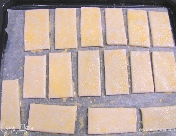 Разбейте яйцо и отделите белок от желтка. Добавьте в желток 1 ч. л. воды и размешайте. Это позволит намного легче намазывать желток. Намажьте кисточкой желток на язычки. Насыпьте равномерно и аккуратно сахар на каждый язычок.