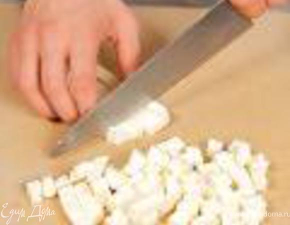 Брынзу нарезать кубиками. Выложить в салат. Салат полить заправкой и украсить свежей зеленью кинзы.