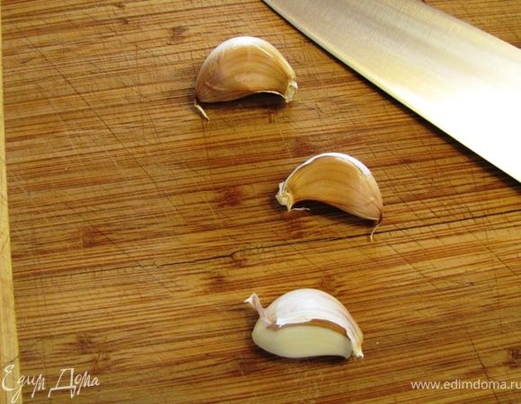 Ударьте плоской стороной ножа по каждому зубчику чеснока, чтобы кожица лопнула. Так вам будет легче его почистить. Срежьте попки и снимите кожуру.
