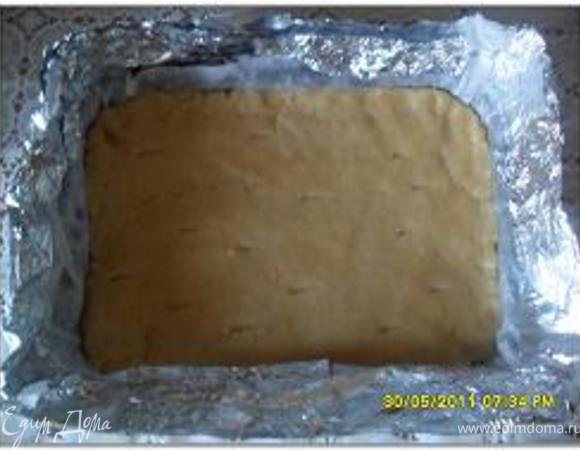 Раскатать тесто на противне, в нескольких местах проткнуть вилкой. На открытой стороне противня поставить бортик из сложенной втрое полоски фольги