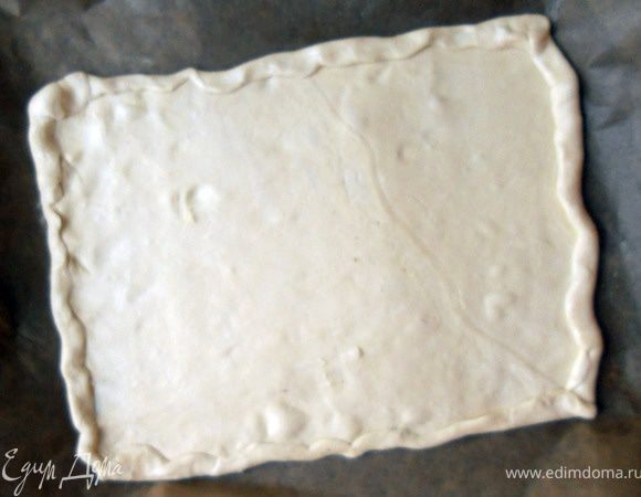 Тесто предварительно разморозить, раскатать, при необходимости формируя небольшие бортики. Проколоть в нескольких местах вилкой. 