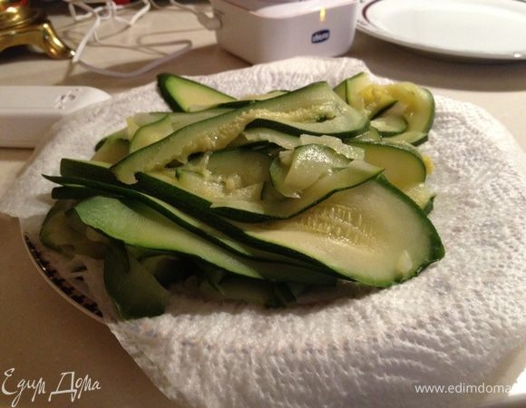 Цукини нарезать продольно на пластины толщиной 0,5 см.Далее припустить их в кипящей,подсоленной воде 2-3 минуты.Вынуть и положить на несколько слоев бумажных полотенец,чтобы удалить жидкость. 