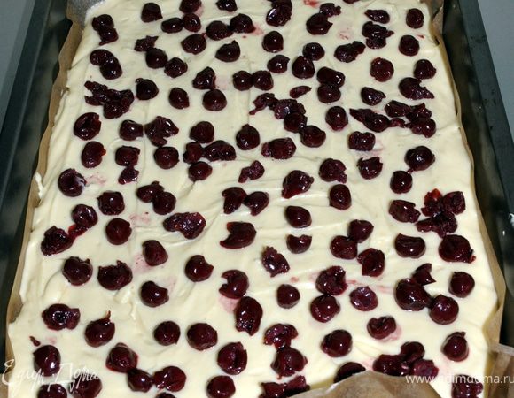 Вылейте тесто в форму. Сверху насыпьте вишню. Выпекать можно в разных формах. Иногда я пеку в большой форме, пирог получается тонким, тогда вишню кладу сверху. Можно выпекать и в круглой разъемной форме. Тогда выложите в форму половину теста, потом — слой вишни и покройте второй половиной теста. Пирог получается высокий с начинкой внутри. Зимой я использую консервированную вишню в собственном соку. На один пирог — одна банка объемом 0,5 л.