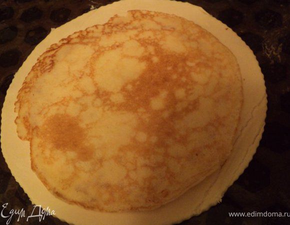 Готовое слоеное тесто разморозить. Из пласта теста вырезать круг на 2 см больше, чем радиус блинов – это будет донышко, и второй круг, больший на 2 см радиуса донышка – это будет верх. Тесто для донышка пирога перенести на противень, застеленный бумагой для выпечки и смазанной растительным маслом. На тесто положить блинчик.