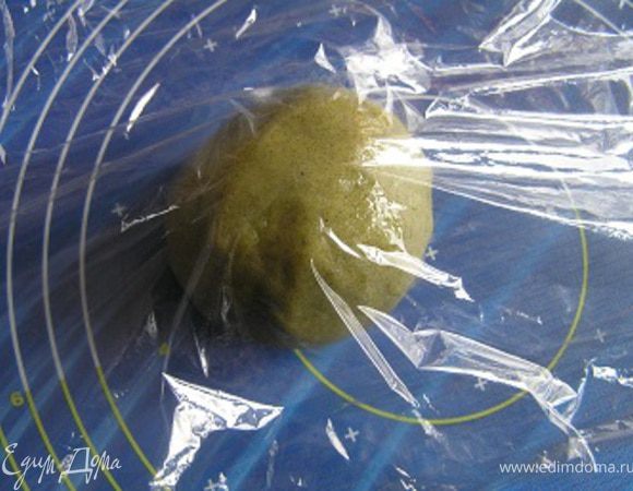 Положить тесто между слоями пищевой пленки на рабочую поверхность,