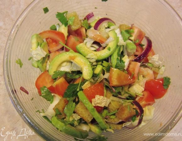 Долейте еще ложку масла в сковороду. Почистите зубчик чеснока и бросьте его в сковороду. Так он отдаст запах, но не сгорит.
Порежьте мякоть хлеба на кубики размером от одного до полутора сантиметров. Так на них образуется хрустящая корочка, но внутри они останутся мягкими.
Положите хлеб в сковороду и хорошо перемешайте крутоны, чтобы масло обволокло их со всех сторон. Если вы не сделаете это хорошо, масло впитается с одной стороны и крутоны получатся жирными и плохо обжаренными. Обжаривайте крутоны до образования корочки, периодически переворачивая их.

Порвите салат на кусочки, мелко порубите кинзу. Помидоры порежьте на небольшие кусочки. Если у вас Черри, порежьте их пополам.

Приготовьте соус. Для этого соедините столовую ложку апельсинового сока, две чайные ложки уксуса и три столовых ложки оливкового масла. Добавьте большую щепотку соли и щепотку перца. Хорошенько перемешайте вилкой или взболтайте в банке с крышкой.

Смешайте все ингредиенты, полейте соусом и еще раз хорошо перемешайте.
Выложите салат на тарелки и посыпьте сверху кунжутом.