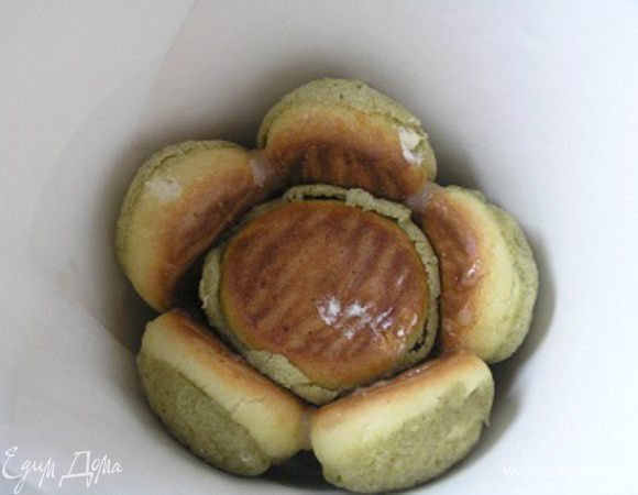 Сборка торта. Из плотной бумаги или картона сделайте конус (можно посмотреть здесь http://www.edimdoma.ru/recipes/33961), поставьте острым концом в высокую чашу. На дно положить первую профитрольку зеленой стороной вниз. Затем каждое следующее пирожное обмакивать в карамели (только той стороной, которая будет соприкасаться с другим пирожным) и выкладывать по кругу одно на другое песочной основой к внешнему краю. 