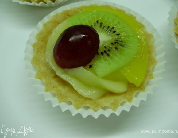 Тонкими ломтиками нарезаем киви и персик, виноград разрезаем пополам. Выкладываем фрукты поверх крема.