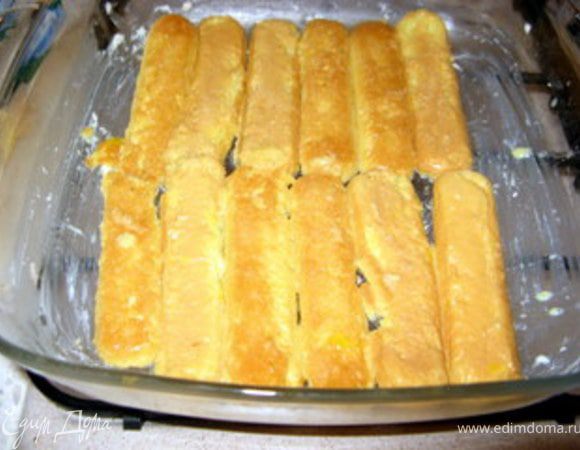 Смазать форму для выпечки сливочным маслом и выложить первый слой савойярди. 