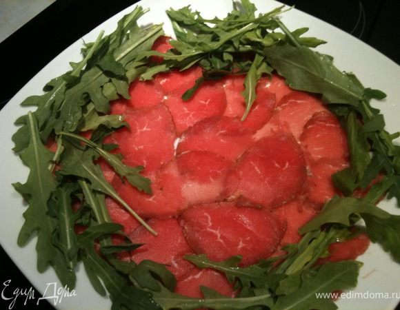 Вокруг мяса выложить рукколу и посыпать тертым Пармезанам. По бокам разложить пармезановые слайсы. Сразу же подавать к столу. Приятного аппетита!