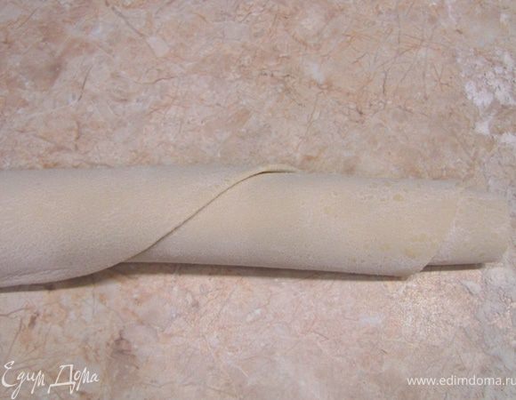 Посыпьте обильно мукой тесто. Скатайте лист теста в рулон. Так будет легче нарезать лапшу.