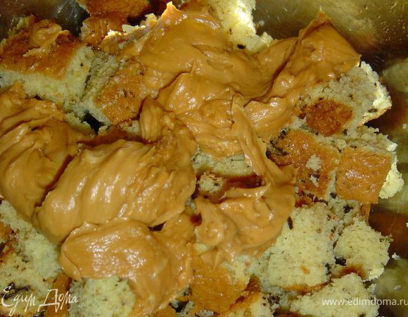 Готовим крем под мастику, взбиваем размягченное сливочное масло с вареной сгущенкой. Маленький корж нарезаем небольшими кусочками и соединяем с 1/3 масляного крема.