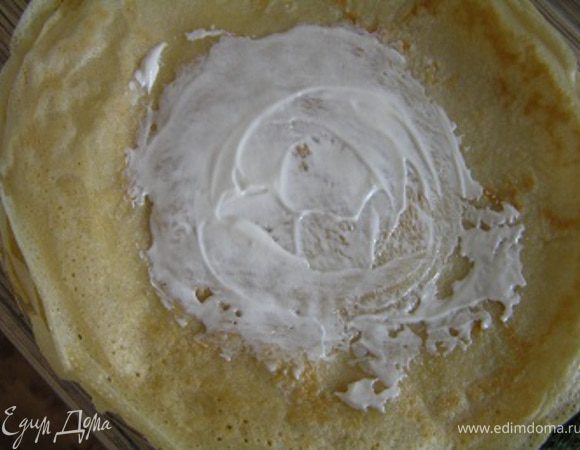 В центр каждого положить ложку сметаны, распределить по поверхности (оставляя края не смазанными на 2-3 см),