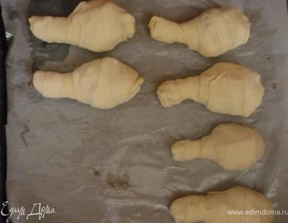 Каждую голень завернуть в полоски теста, получатся «куколки» голеней, хорошо закрепить края, чтобы во время выпечки не вытекал сок. Противень выложить бумагой пекарской, выложить голени, взбить 1 яйцо с 1 ст.л раст.масла и смазать голени этой смесью