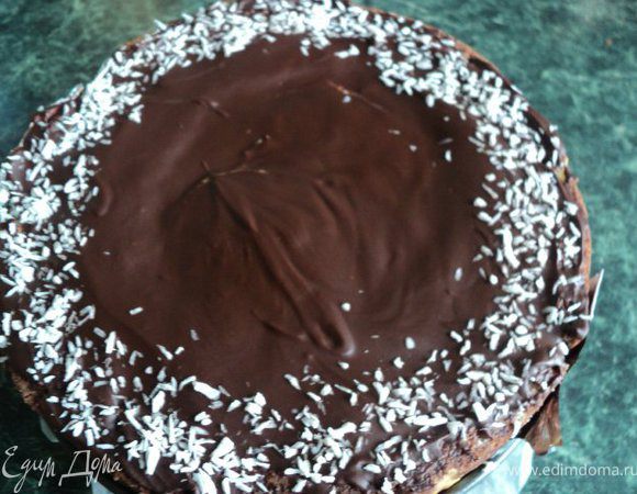 Шоколад растопить вместе со сливками и маслом в микроволновке или на водяной бане.
Вылить на торт, распределить по поверхности. Края обсыпать кокосовой стружкой, поставить на 30 мин в холодильник для охлаждения.
