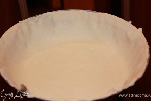 Раскатать тесто достаточно тонко, и положить пласт в смазанную сливочным маслом форму. Уложить тесто так, чтобы были закрыты дно и бока формы. Срезать сверху лишнее.