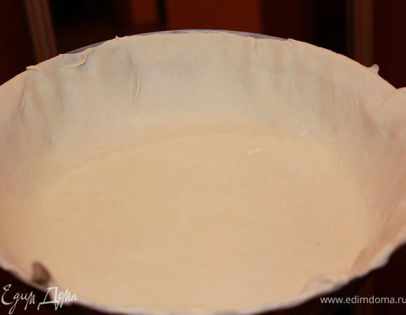 Раскатать тесто достаточно тонко, и положить пласт в смазанную сливочным маслом форму. Уложить тесто так, чтобы были закрыты дно и бока формы. Срезать сверху лишнее.