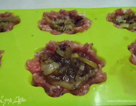 Можно готовить на протвине,но я беру форму для кексов.
 Фарш выложить  в  формочки,сделать небольшую выемку ,в которую  кладем жареный лук