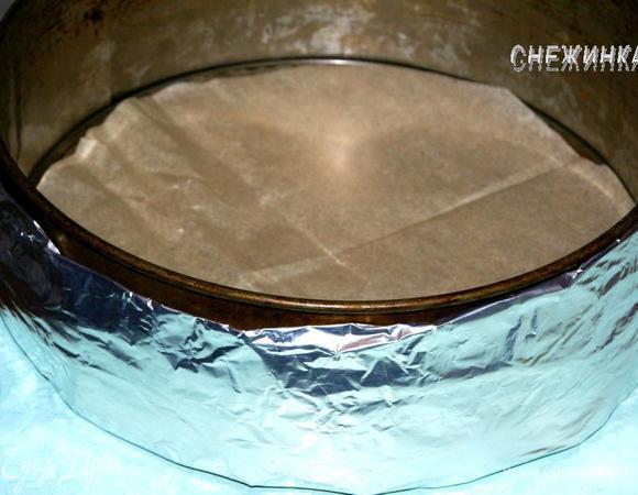 Затем добавьте крутой кипяток (я наливала, ориентируясь на неполный стакан), быстро перемешайте и вылейте в форму. Дно формы я выстелила кругом из пергаментной бумаги, ни бумагу, ни форму ничем не смазывала. Вокруг формы я обмотала фольгу, в которой завернуто мокрое полотенце. Это нужно для того, чтобы бисквит получился ровным. С моей старой духовкой этот способ очень выручает.
