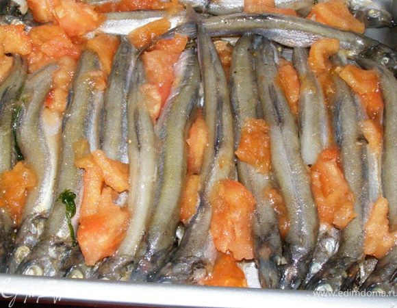 Помидор очистим от кожицы и семян. Порежем на кусочки. Воткнем кусочки помидора между мойвой