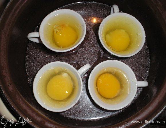 Готовим яйца. Для этого берем маленькие чашечки (у меня кофейные), смазываем их сливоным маслом и вливаем в них яйцо. Чашечки ставим в кастрюлю с кипятком и варим их таким образом до готовности.