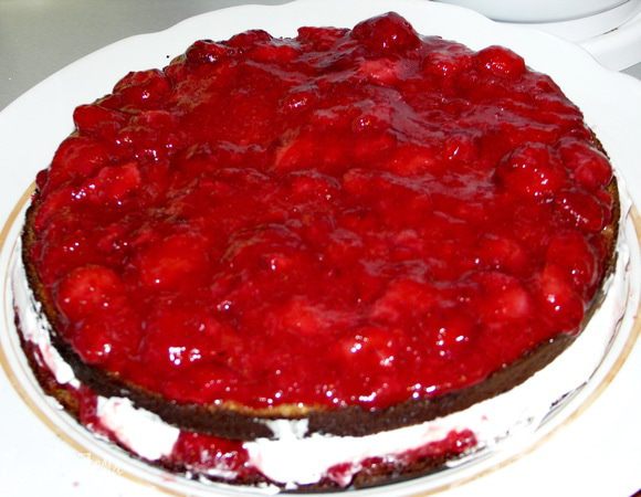 Накрываем вторым коржом пропитанной стороной вниз.Снова пропитываем корж сиропом.Сверху вторую часть ягодного пюре.Следом 1/3 часть сливок.