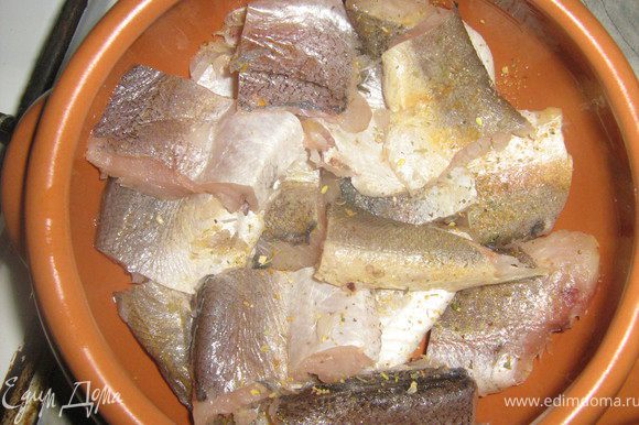 Горшочек смазать растительным маслом, выложить хек, посыпать специями для рыбы.