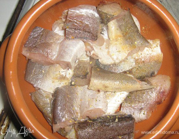 Горшочек смазать растительным маслом, выложить хек, посыпать специями для рыбы.