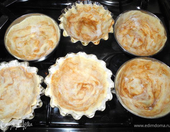 Затем взять формы. Я использую для этих пирожных металлические кокотницы, очень удобно. Слегка смазать формы маслом и распределить тесто по форме. Надо постараться сделать высокие бортики. Слой теста будет тонким. Несколько формочек мне не хватила и я взяла формы для корзиночек, положила туда бумажные формочки для кексов, дальше всё, как в первом варианте, только без смазывания форм. 