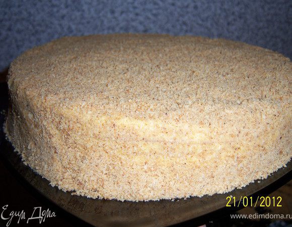 Положите сверху второй корж и проделайте то же самое. <br />
В конце обмажьте верх и бока торта кремом и посыпьте орехами. 