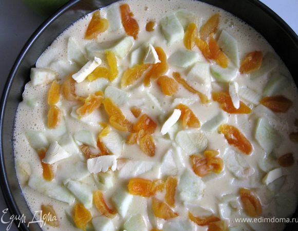 Вылить тесто в форму, сверху выложить яблоки, очищенные от кожуры и порезанные на небольшие дольки, и курагу, порезанную на кусочки. Добавить несколько кусочков слив.масла. 