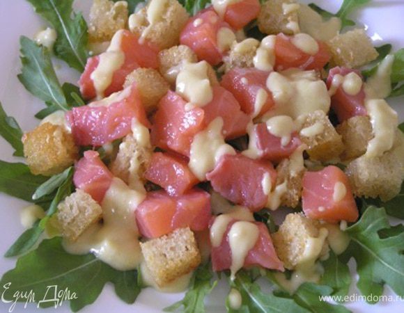 Выложить крутоны и нарезанную небольшими кубиками семгу на листья рукколы, полить соусом.