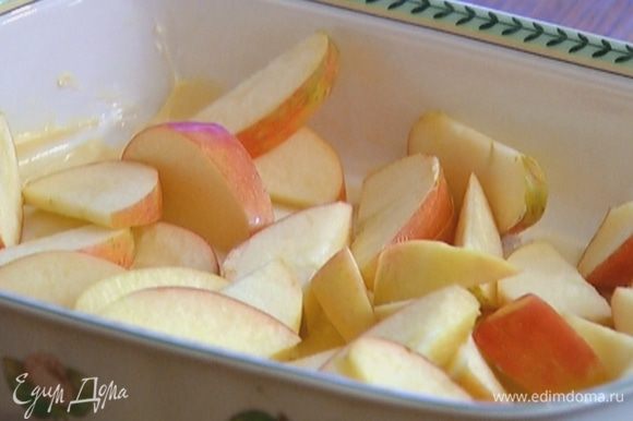 Жаропрочную форму немного смазать сливочным маслом, выложить в один слой яблоки и посыпать их сахаром.