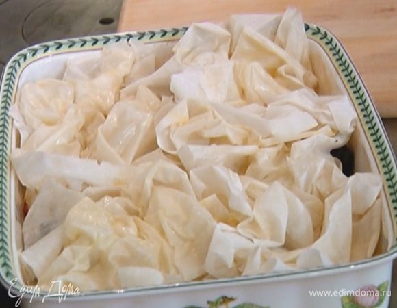 Запеченные яблоки вынуть из духовки, разложить на них оставшийся неразрезанный чернослив, сверху прикрыть все скомканными листами теста фило, уложив их один рядом с другим.