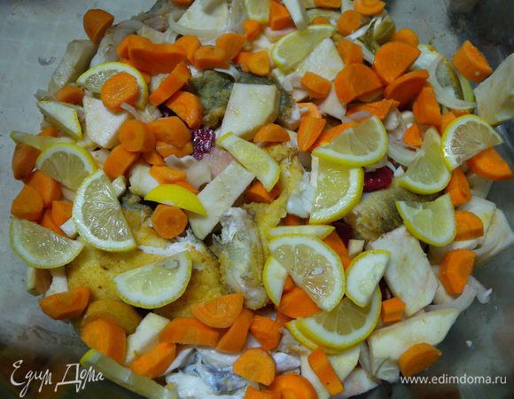 Рыбу переложить в огнеупорную посуду перекладывая (пересыпая) овощами. Залить кипятком почти до верха. Накрыть крышкой. 
