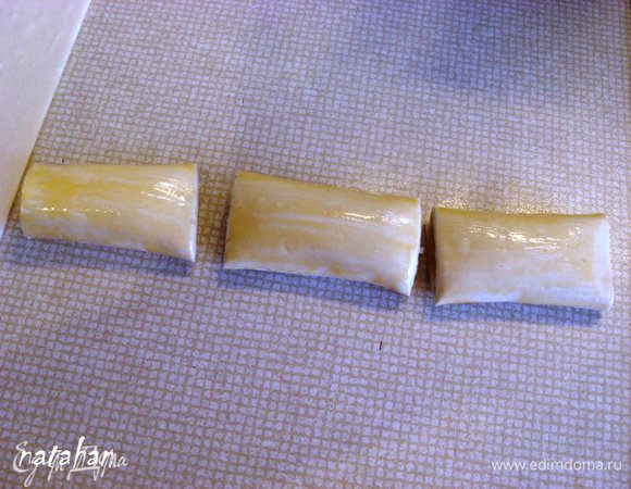 Свернуть из пласта теста с фаршем рулетики. Обмазать его желтком и разрезать на 3 части.