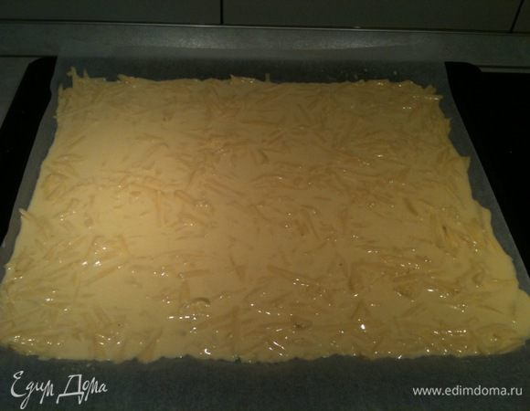 Протвинь застелить бумагой для выпечки. Выложить яично-сметанно-сырную массу на противень, равномерно распределяя ее по нему. Поставить в разогретую до 180 градусов духовку на 5-10 минут.