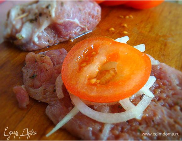 На каждый кусочек мяса выложить с обмазанной стороны и с одного края немного лука, сверху-кружок помидора-свернуть в рулетик и закрепить зубочисткой.