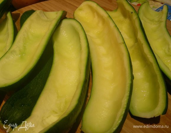 Разогреваем духовку до 180 гр. Кабачки разрезаем напополам, ложечкой вынимаем мякоть. Я лодочки кабачков немного смазываю маслом и предварительно запекаю минут 20, чтобы они были мягче, ведь начинку мы закладываем уже готовую. Можно обойтись и без этого.
