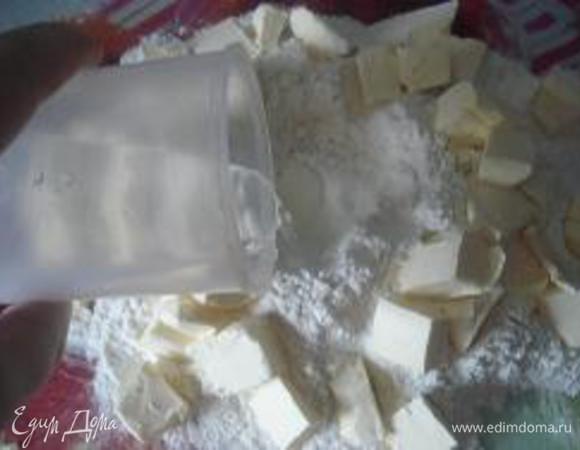 Приготовление теста:
Муку просеять с разрыхлителем, выложить горкой на разделочную доску. Сделать углубление. В углубление налить холодную воду и добавить щепотку соли. Масло нарезать мелкими кусочками и выложить по кругу.