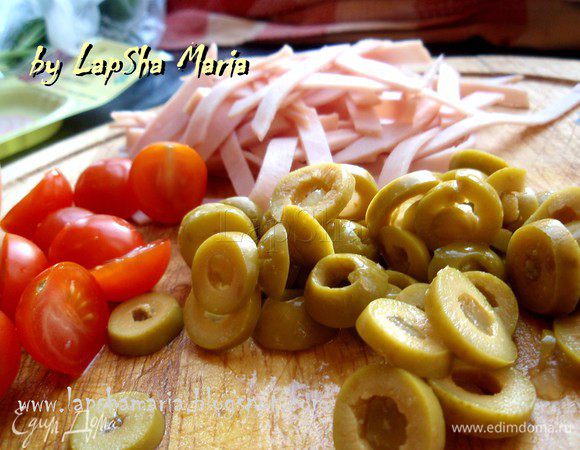 Помидоры черри нарежем на половинку, ветчину на тонкие полосочки, оливки кружками. Оливки я взяла с грейпфрутом, очень вкусные. И придают салату изюминку.
