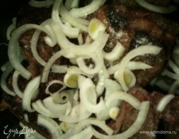 На мясо выложить вторую часть лука и залить вином.