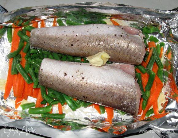 На фольгу выложить морковь, фасоль. Поперчить .Сверху положить рыбу.
Добавить 50г сливочного масла, 5-6 столовых ложек белого вина. Духовку нагреть до 200 градусов.
Рыбу завернуть в фольгу, подвернув ее края так, чтобы при  запекании не вытекала жидкость и не выходил пар. Поставить  рыбу в духовку на 30 минут.
