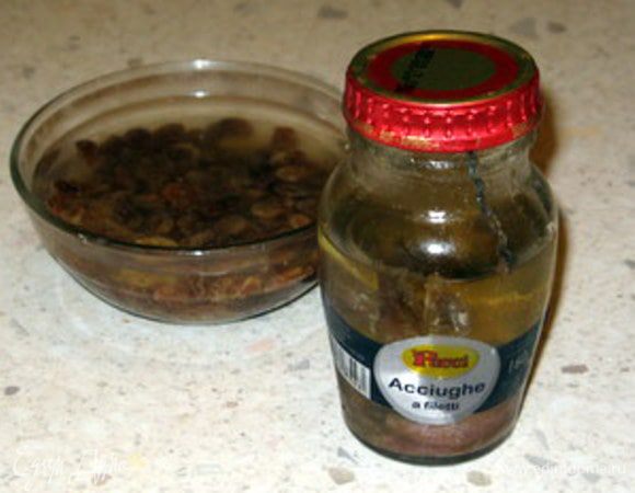 Замочить изюм горячей водой.Мелко порезать петрушку и анчоусы.