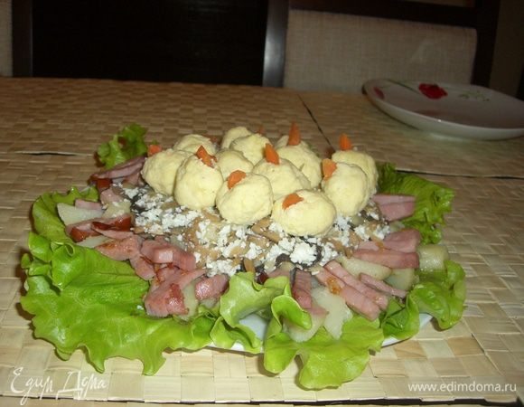 Картофель и капченное мясо выкладываем на листья салата в виде гнезда, добавляем туда лук с грибами и нарезанным белком. Вареную морковку охлаждаем и очищаем от кожуры.  Скатываем небольшие шарики из сырно-чесночно-желтково-майонезной массы, в середину каждого из которых вкладываем половинку грецкого ореха. Теперь укладываем их в гнездо.