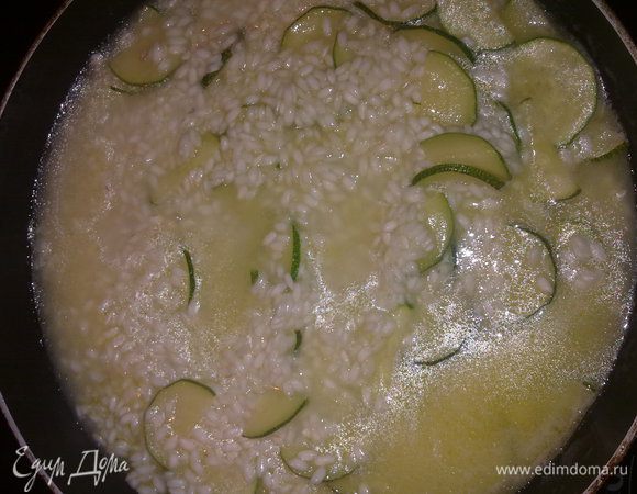 Добавить рис и оставить на огне 1 минуту постоянно помешивая, затем влить один половник горячего бульона и готовить на слабом огне пока рис не дойдет до состояния "аль денте". По мере выкипания жидкости подливать бульон.