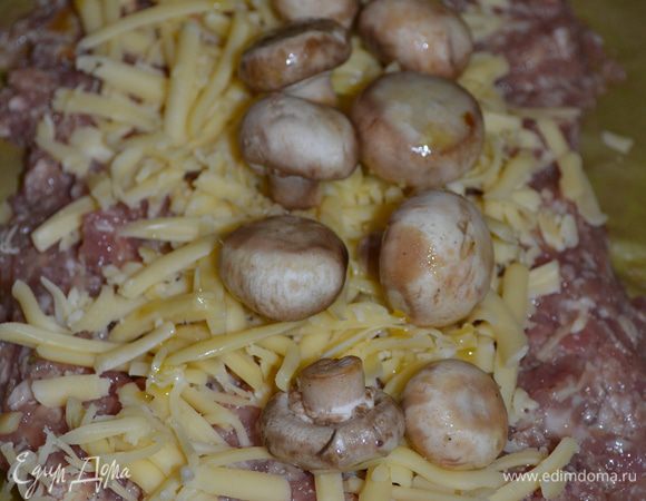 Фарш выложить на пергамент, толщиной 1 см.Сверху уложить начинку: сыр и шампиньоны. 