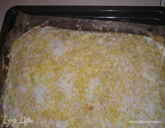 Посыпаем сверху миндальной стружкой, немного придавливая ее к тесту. По миндальной стружке посыпаем 50 гр сахара и цедру 1/2 лимона.