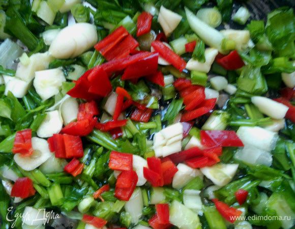 Лук (пару перышек отложить), чеснок (очистить), и перец (предварительно удалить семена и перепонки, промыть) измельчить. Разогреть в сковороде пару ложек масла и на умеренном огне обжарить 1-2 минуты, переложить в отдельную посуду. 