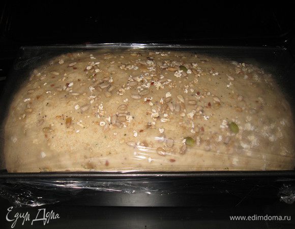 Переложила готовое тесто в форму, накрыла пленкой дала подойти 20 мин, затем смазала водой и посыпала семенным миксом. 